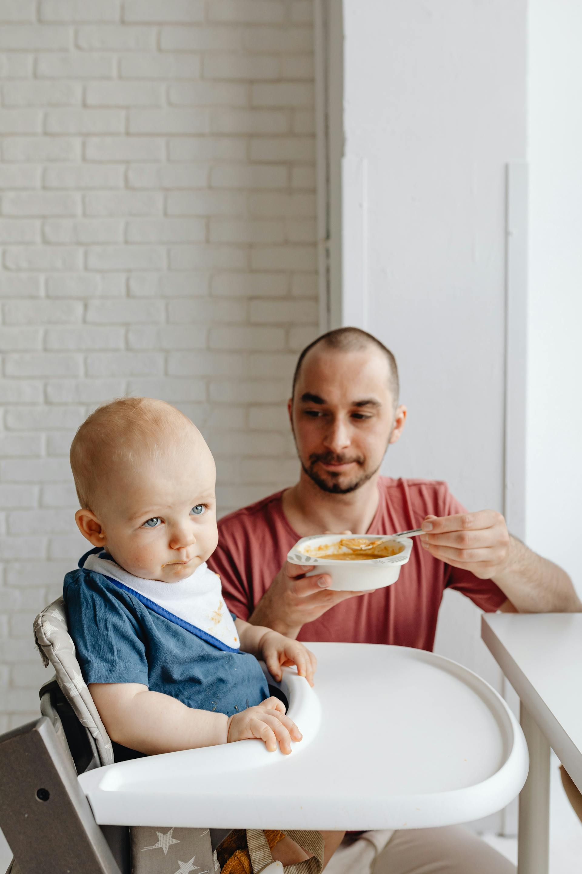 Parent qui donne une cuillère de purée à bébé pendant la diversification alimentaire