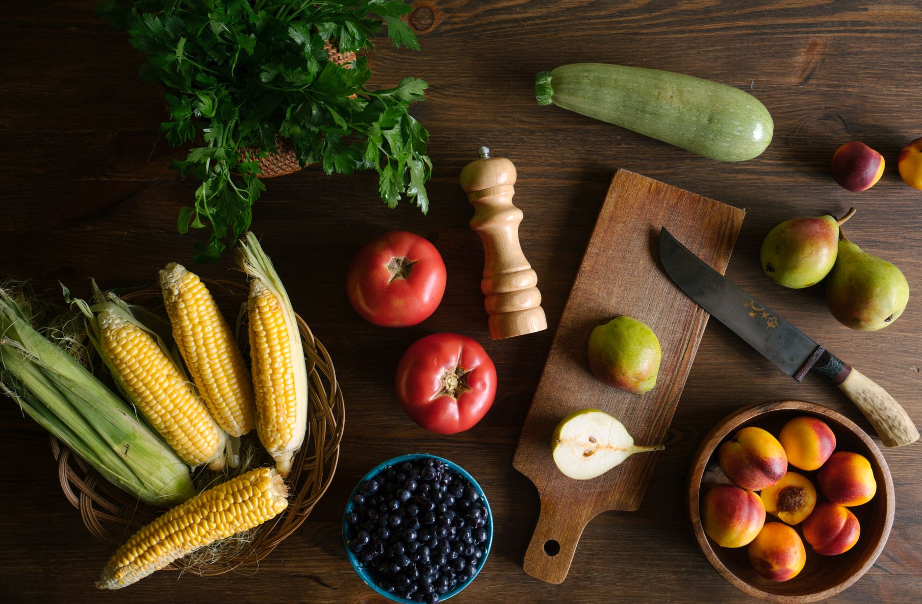Courgette fraîche entière posée sur une planche en bois entourée de légumes du potager